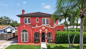 A red two-story house with a front entrance, a small porch, and a mailbox.