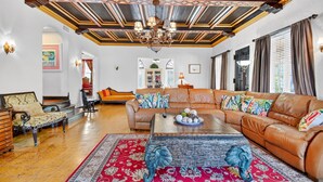 A spacious living room with a large leather sofa, a coffee table with decorative items, and a patterned rug.