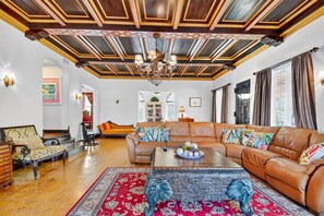 Un salón amplio con un sofá de cuero grande, una mesa de centro con objetos decorativos y una alfombra estampada.