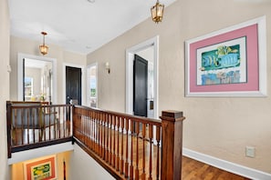A staircase with wooden balusters and a handrail, leading to an upper floor. - Historic 1925 Estate · Pool · Sleeps 14 · 3.5 Baths · Walk to Marina (West Palm Beach)