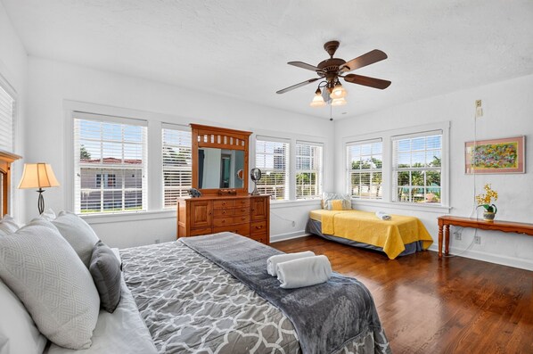 A bedroom with a bed, dresser, vanity, and a ceiling fan. - Historic 1925 Estate · Pool · Sleeps 14 · 3.5 Baths · Walk to Marina (West Palm Beach)