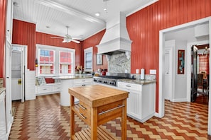 Una cocina con piso de espiga, muebles blancos y una isla central con encimera de madera.