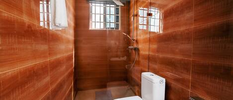 Un baño con inodoro, ducha y ventana.