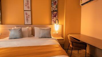 Una habitación de hotel con cama, mesita de noche, silla y una obra de arte en la pared.