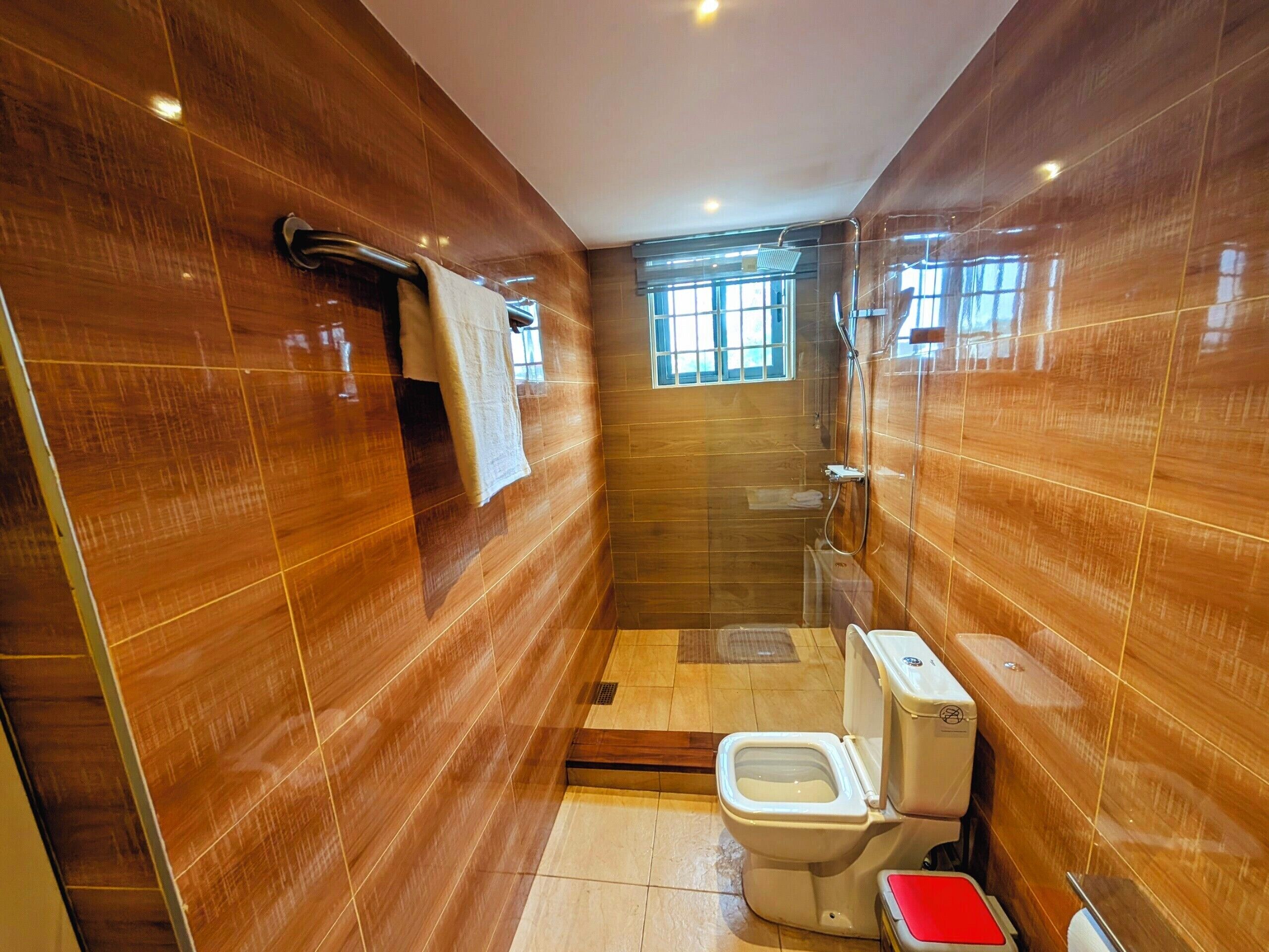 Een badkamer met toilet, douche en raam.