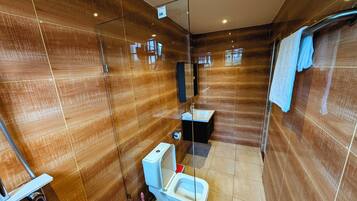 Un bagno moderno con box doccia in vetro, un water e un lavandino.