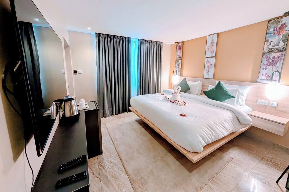 Une chambre d’hôtel avec un lit, une télévision, un bureau et une fenêtre avec des rideaux.