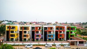 A row of colorful, modern buildings with balconies, likely residential or commercial properties. - Condos De La ChiChi (Kumasi)