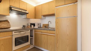 A modern kitchen with wooden cabinets, a stainless steel range hood, a microwave, a kettle, and a toaster.