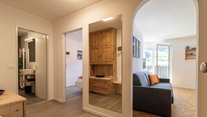 A modern interior with a wooden dining table, a sofa, and a kitchen area with wooden cabinets.