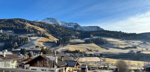 Eine Berglandschaft mit einem Dorf im Vordergrund, mit traditionellen Häusern und freiem Blick auf die Berge.