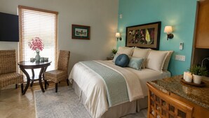 A bedroom with a bed, a chair, a table, and a TV. - Hanalei Hideaway-Oceanfront, Mtn & Waterfall Views, Top Floor, No Stairs (Princeville)