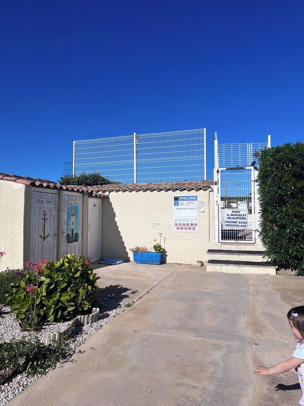 Un edificio con tetto in tegole, un'area recintata e un cartello che indica una zona per tecnologia e una piscina.