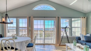 Una habitación amplia con una mesa de comedor, sillas, un sofá y un balcón con vistas.