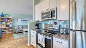 Una cocina moderna con armarios blancos, electrodomésticos de acero inoxidable y un salpicadero de azulejos azules.