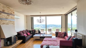 Ein geräumiges Wohnzimmer mit großem Fenster, Kamin und Blick auf die Stadt.