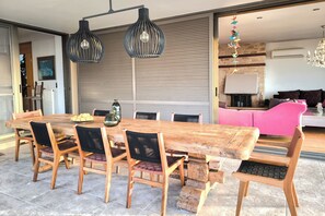 A spacious dining area with a large wooden table and chairs, a modern chandelier, and a fireplace. - Villa Mirtylla luxury retreat. Pool Gym (Heraklion)