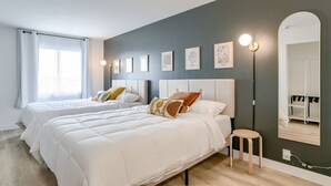 A modern bedroom with two beds, a large mirror, and artwork on the wall. - 5 min. to Lincoln's top attractions. 2 Queens, kitchenette, WiFi & outdoor space (Lincoln)