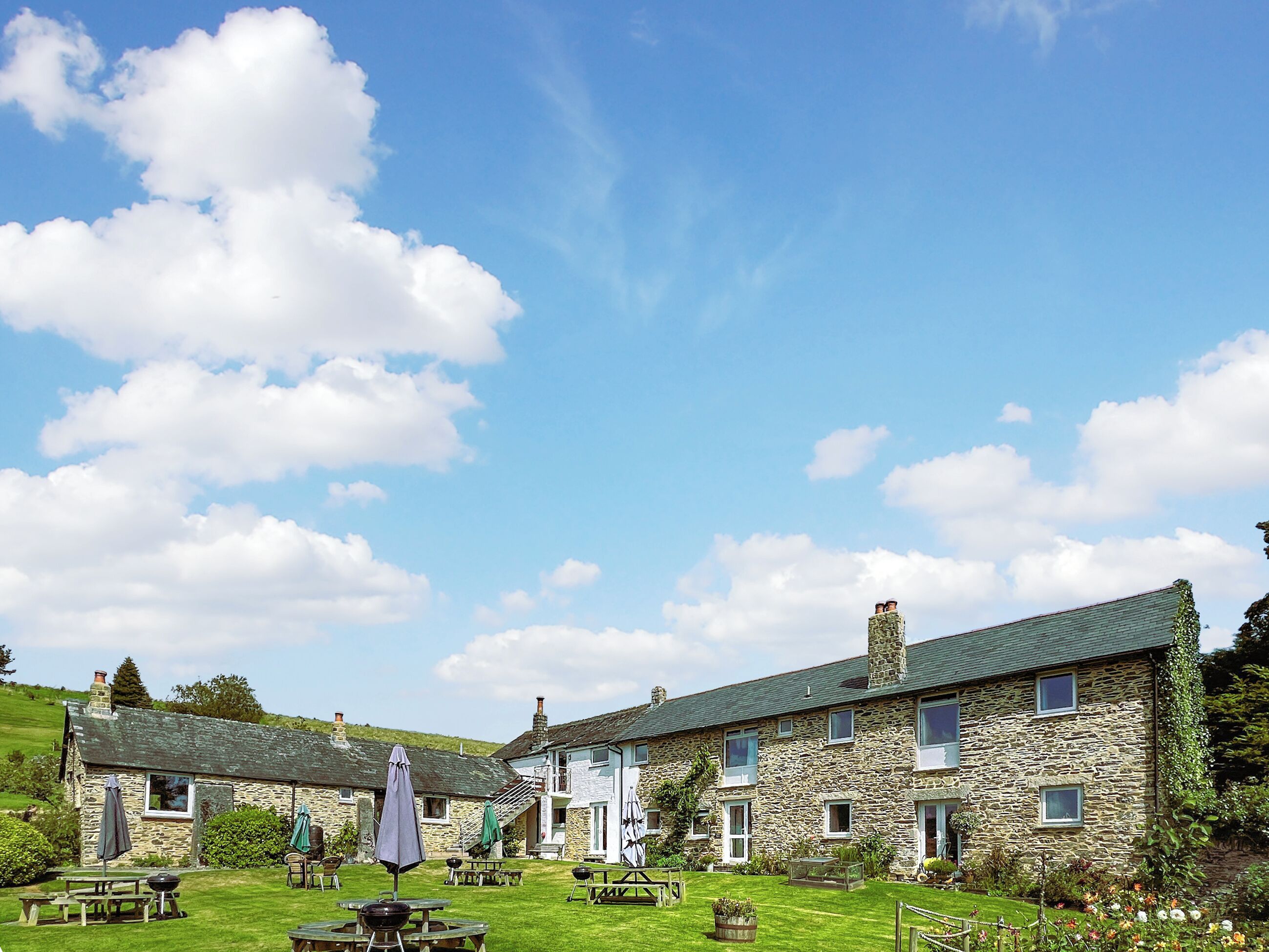A stone building with multiple windows and a well-maintained lawn.