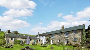 A stone building with multiple windows and a well-maintained lawn. - Linney Cottage - UK48986 (Looe)