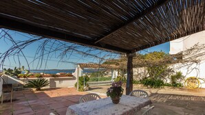 Une terrasse extérieure avec une table et des chaises, un pot de fleurs et une vue sur la mer.