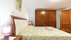 Une chambre à coucher avec un lit, une table de chevet, une lampe, une armoire et un tableau au mur.