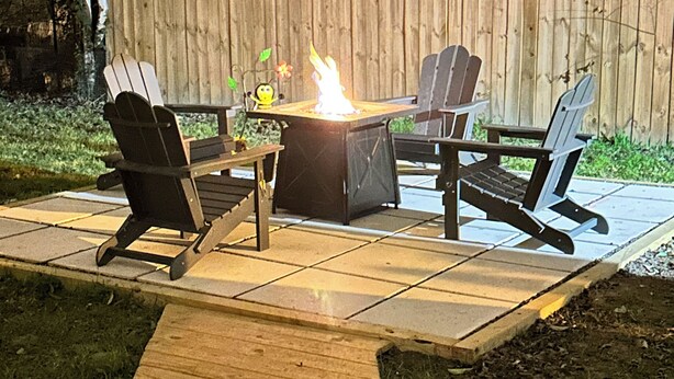 Ulkoterassi, jossa on nuotiopaikka, kaksi Adirondack-tuolia ja puinen terassi.