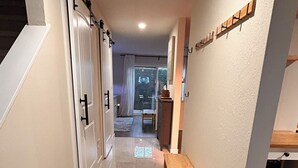 Un pasillo con un banco, una puerta y una ventana con cortinas.