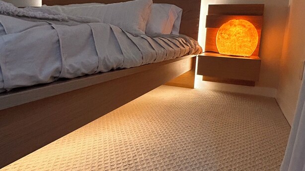 Un dormitorio con cama, una mesita de noche con lámpara y arte abstracto en la pared.