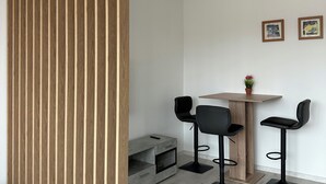 A modern room with a wooden partition, a round table with two chairs, a small cabinet, and a potted plant. - Comfort vacation apartment NeuBau Merzig (Merzig)