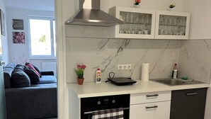 A modern kitchen with a built-in oven, a stove, and a microwave. There is a window above the sink, and a small plant on the countertop. - Comfort vacation apartment NeuBau Merzig (Merzig)