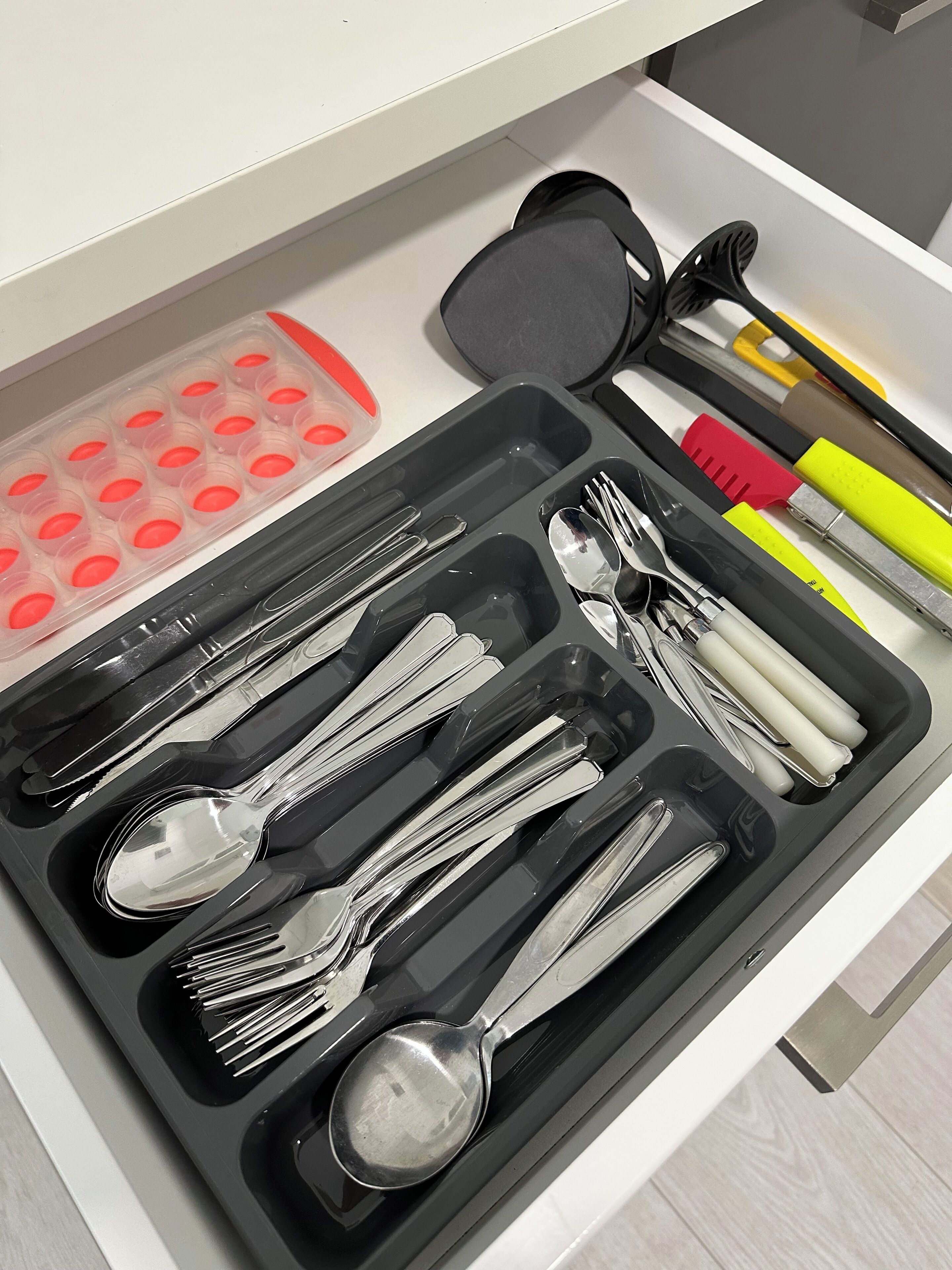 Un cassetto contenente utensili da cucina, come cucchiai, forchette e coltelli, ordinati in scomparti.