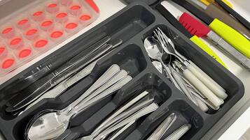 Un cassetto contenente utensili da cucina, come cucchiai, forchette e coltelli, ordinati in scomparti.