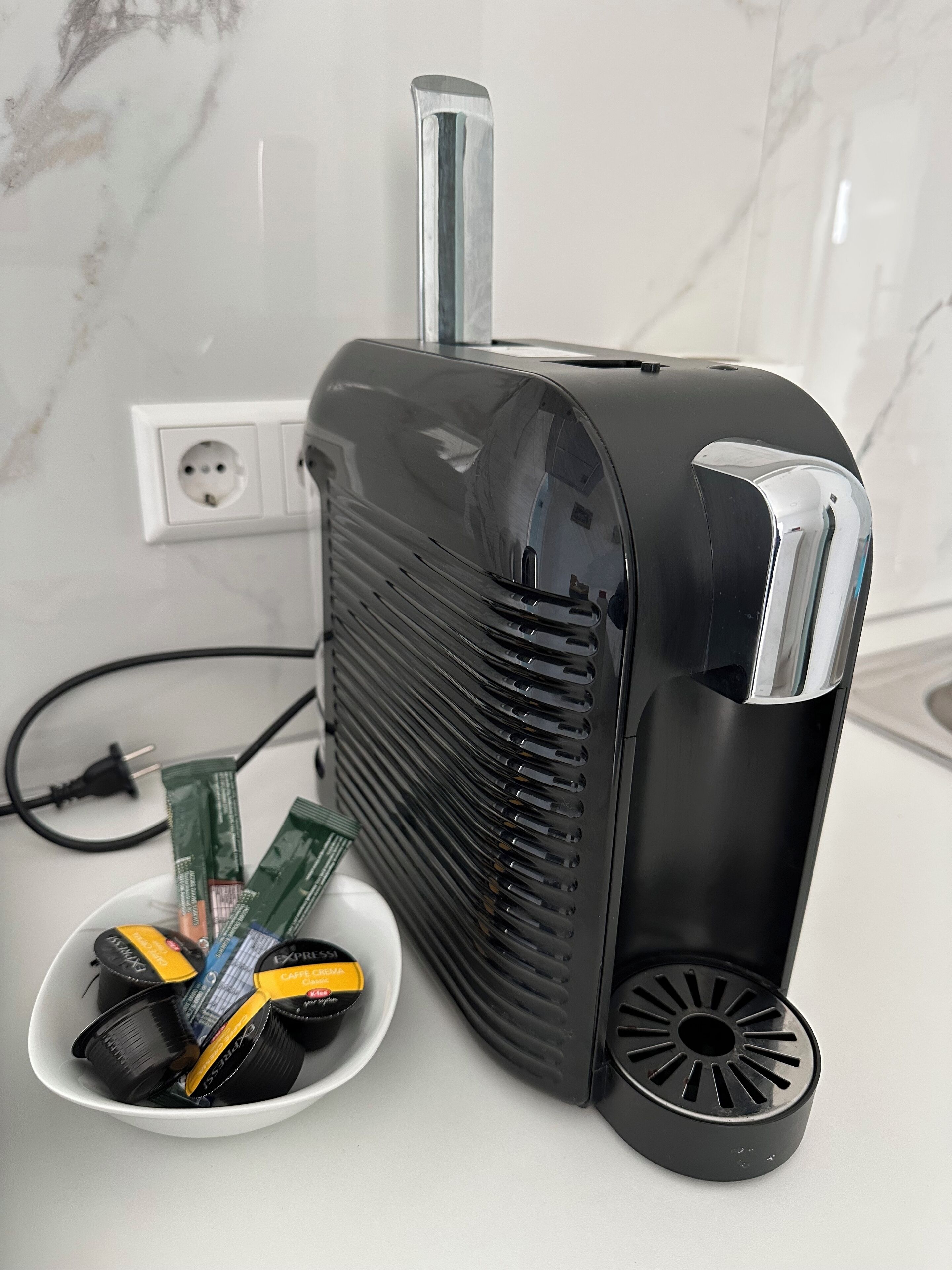 Un radiateur portatif noir, doté d’un câble d’alimentation branché sur une prise murale.
