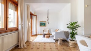 A modern living room with a sofa, a coffee table, a potted plant, and a view of the outdoors through a window. - Spacious Villa with Pool, BBQ and Tennis Courts (Lazio)