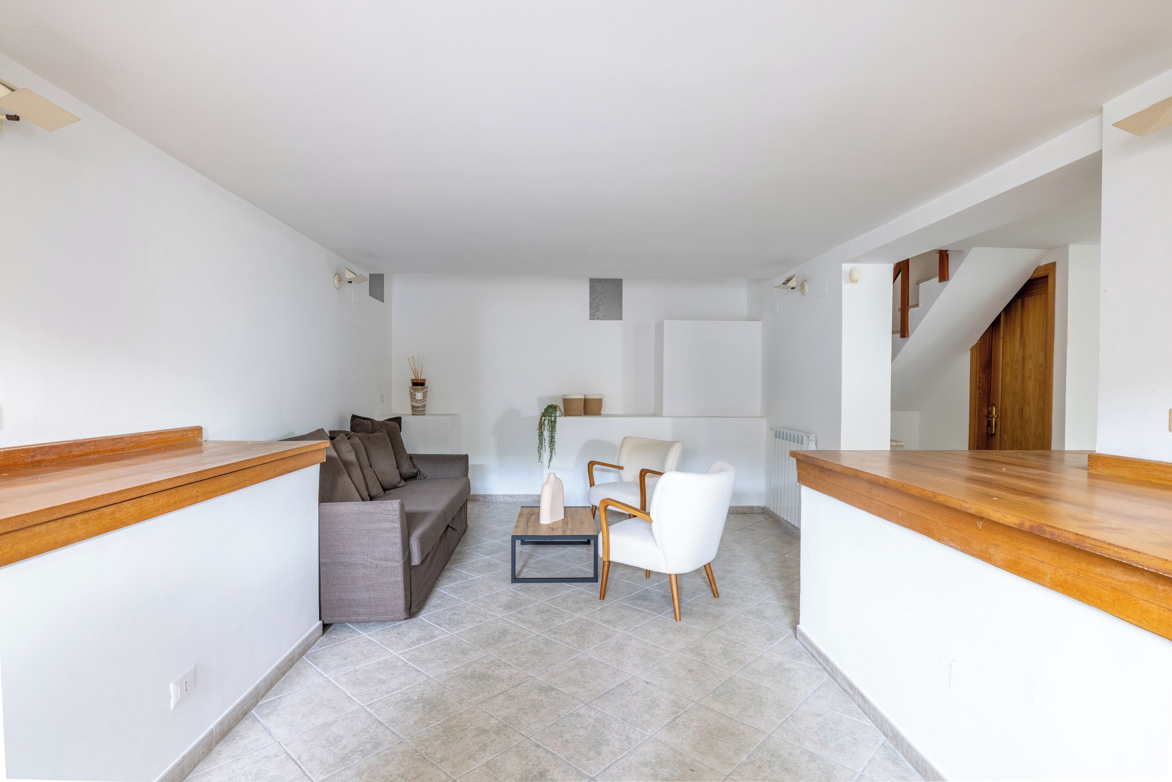 A modern living area with a sofa, two chairs, a coffee table, and a wooden counter.