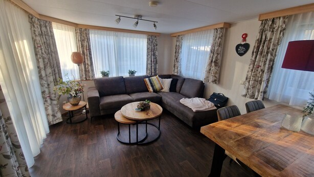 Ein Wohnzimmer mit Ecksofa, rundem Couchtisch, Esstisch und Deckenventilator.