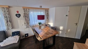 Ein kleiner Wohnraum mit Holztisch, grauem Sofa und einer weißen Tür.