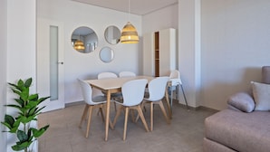 A modern dining area with a wooden table and white chairs, surrounded by three round mirrors and a hanging light fixture.