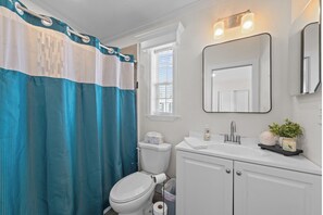 A bathroom with a white toilet, a white sink, a mirror, and a shower curtain. - Sunny Gulf Coast Getaway-Near Beach-Shared Pool! (Fort Myers Beach)