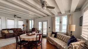 A spacious living room with a wooden floor, a dining table, and a sofa.