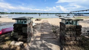 A wooden pathway leading to a beach with a view of boats on the water.