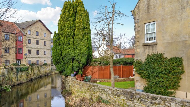 Un canal étroit, bordé d’un côté par des murs de pierre et de l’autre par une rangée d’immeubles dotés de fenêtres et de portes.