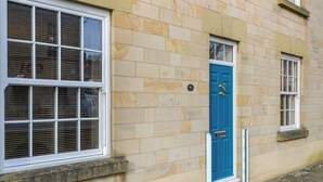 Un bâtiment avec une porte bleue, des murs en pierre de couleur beige et des fenêtres à cadre blanc.