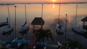 A marina with several boats docked, a small hut, and a sunset in the background.