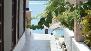 A narrow, tiled pathway leading to a balcony with a view of the sea.