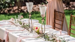 A table set for a formal outdoor event with glassware, plates, and floral centerpieces. - GNV Downtown Estate- Sleeps 16 - Groups & Events (Gainesville)