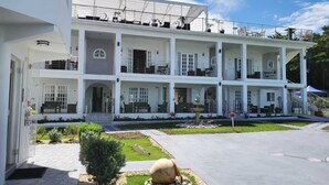 A multi-story hotel with balconies, outdoor seating, and a fountain. - Lavender Moon Villas (Ocho Rios)