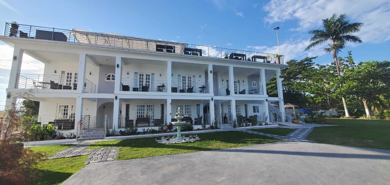 A multi-story building with balconies, a fountain, and a well-maintained lawn.