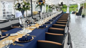 A long table set for a formal event under a tent, with wicker chairs and a stone floor. - Lavender Moon Villas (Ocho Rios)